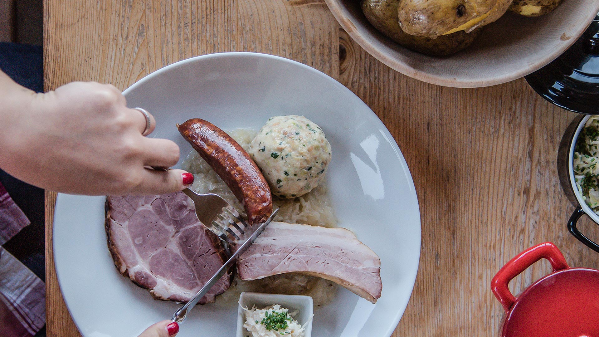 A typical autumn dish on which a customer is intent on cutting meat, served with dumplings and sausages. 