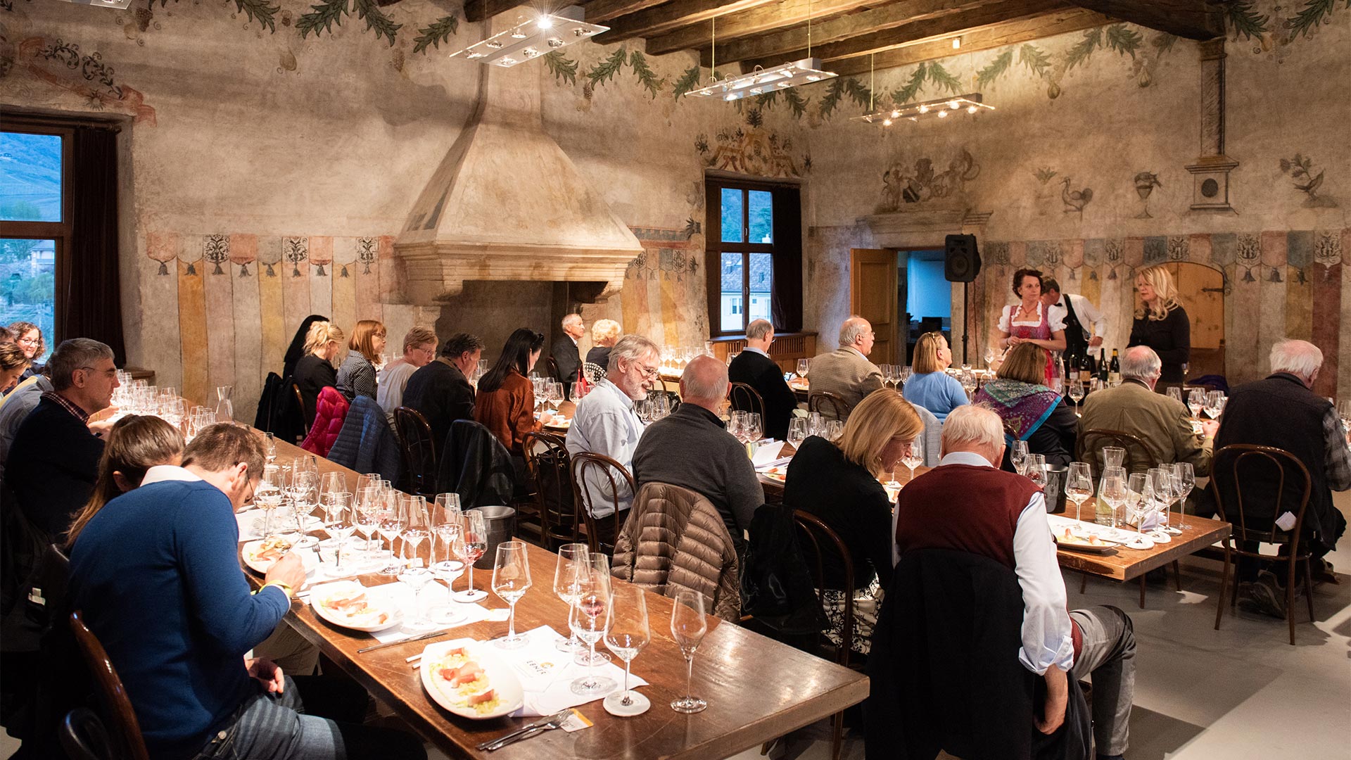 Gruppi di clienti intenti a mangiare all'interno di un ristorante tradizionale a Bolzano stanno per vedere un piccolo spettacolo organizzato dai ristoratori.