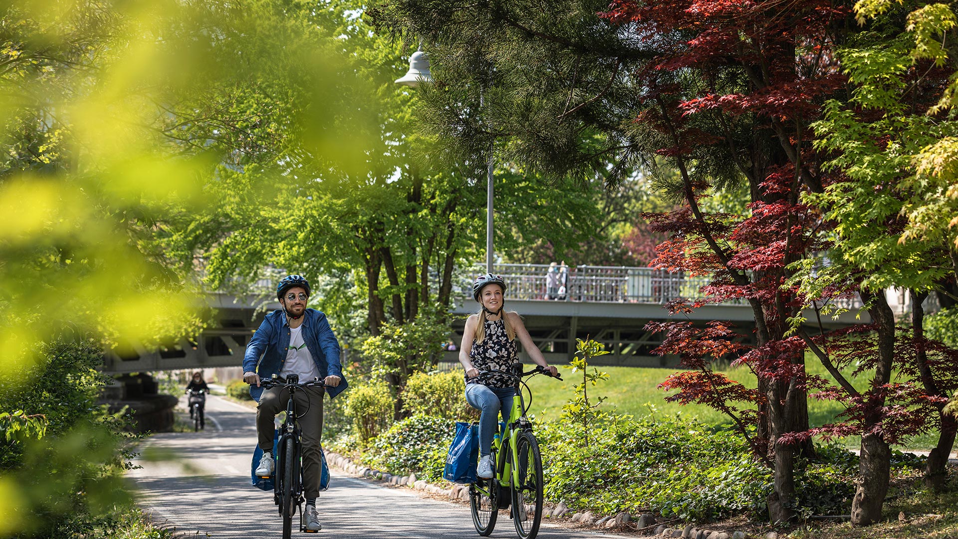 A couple is cycling along the Bolzano cycle path near the Prati del Talvera.