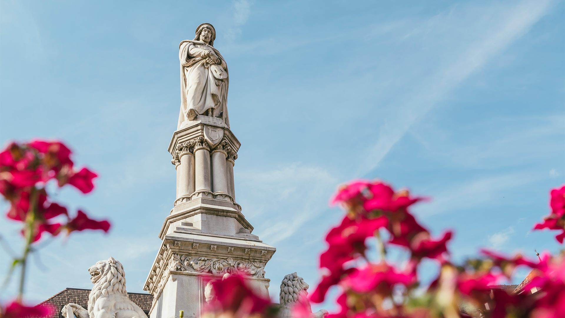 Walther v. der Vogelweide - Statue in der Mitte des Waltherplatzes an einem sonnigen Tag in Bozen.