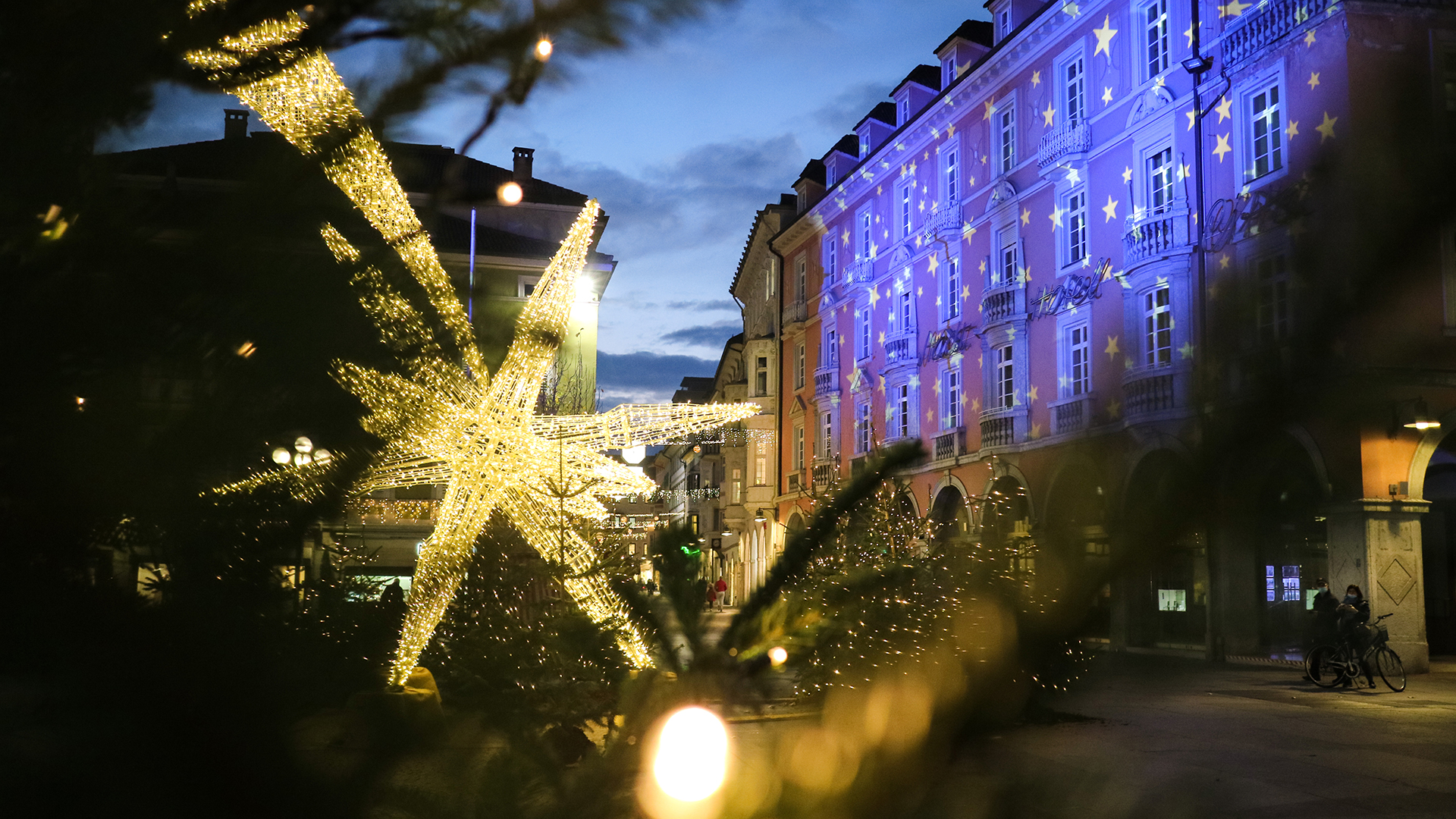 Bozen an einem Weihnachtsabend, an dem auf dem Waltherplatz ein sternförmiges Licht steht und die Gebäude entsprechend den Festlichkeiten beleuchtet sind.