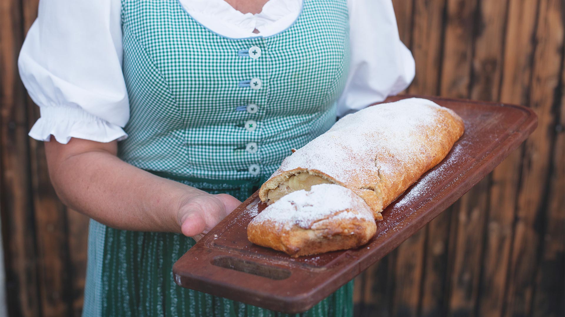 Schneidebrett mit frisch gebackenem Brot, gehalten von einer Kellnerin in einem typischen Südtiroler Restaurant.