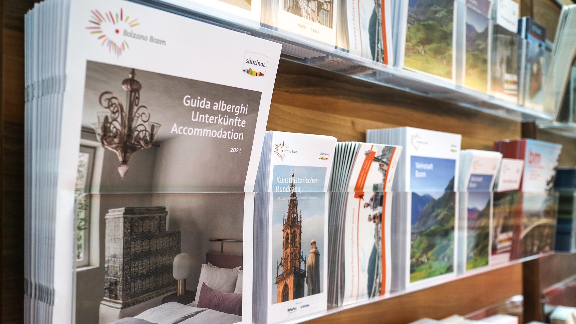 Volantini e itinerari poggiati sugli scaffali degli uffici informativi permettono ai turisti di trovare l'ispirazione su quale punto di interesse a Bolzano visitare nelle loro vacanze .
