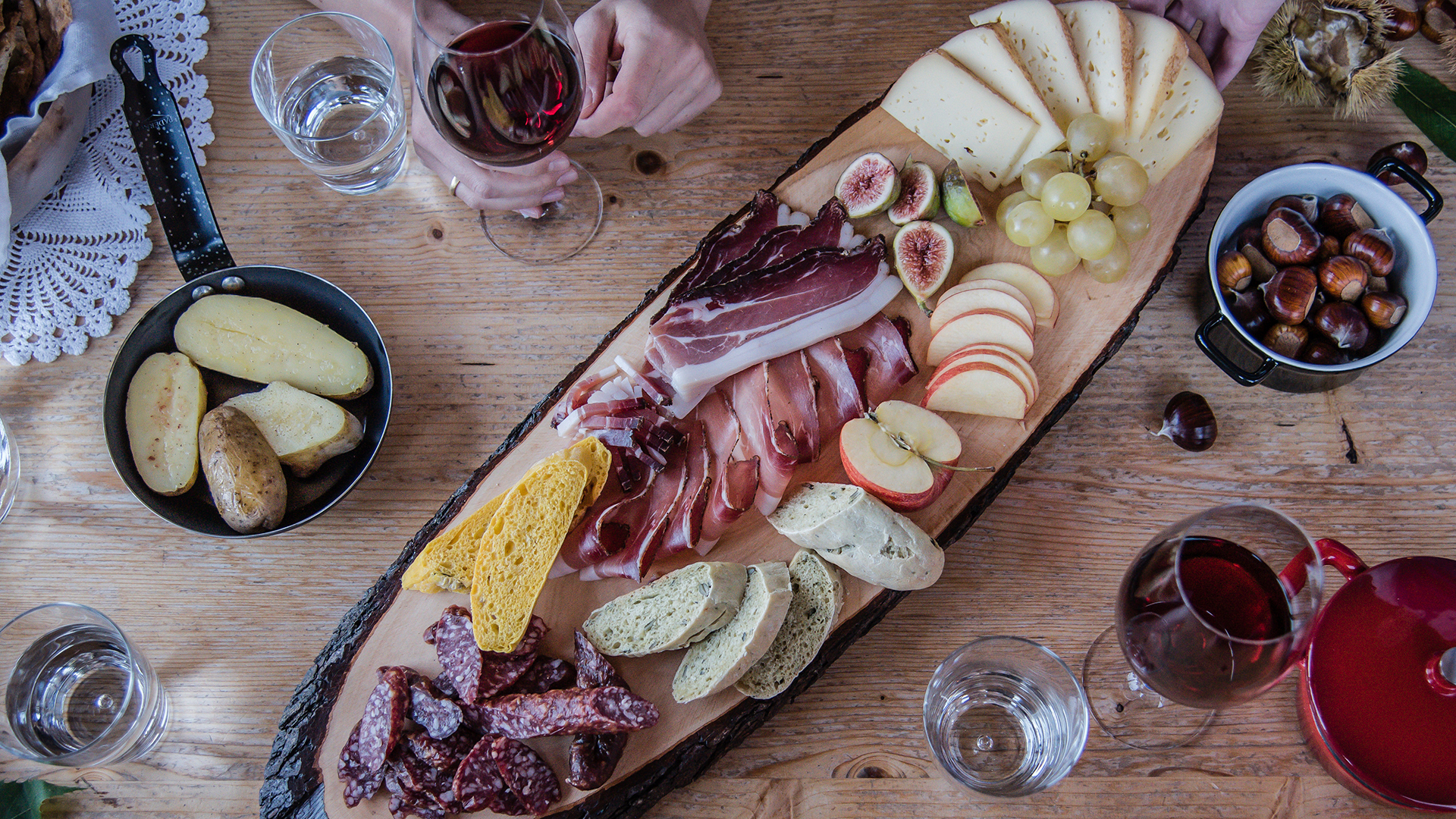 Piatto tradizionale dell'enogastronomia di Bolzano, con dei piatti di carne e salumi accompagnati da un bicchiere di vino rosso.