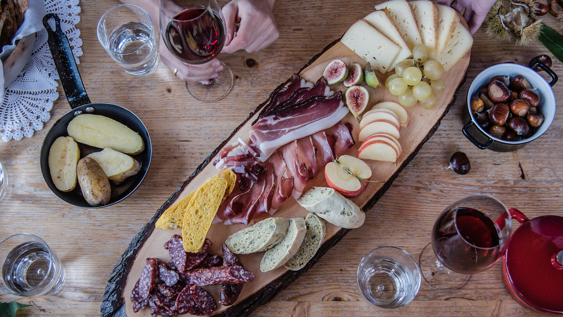 A traditional dish of Bolzano food and wine, with meat and sausage dishes accompanied by a glass of red wine.