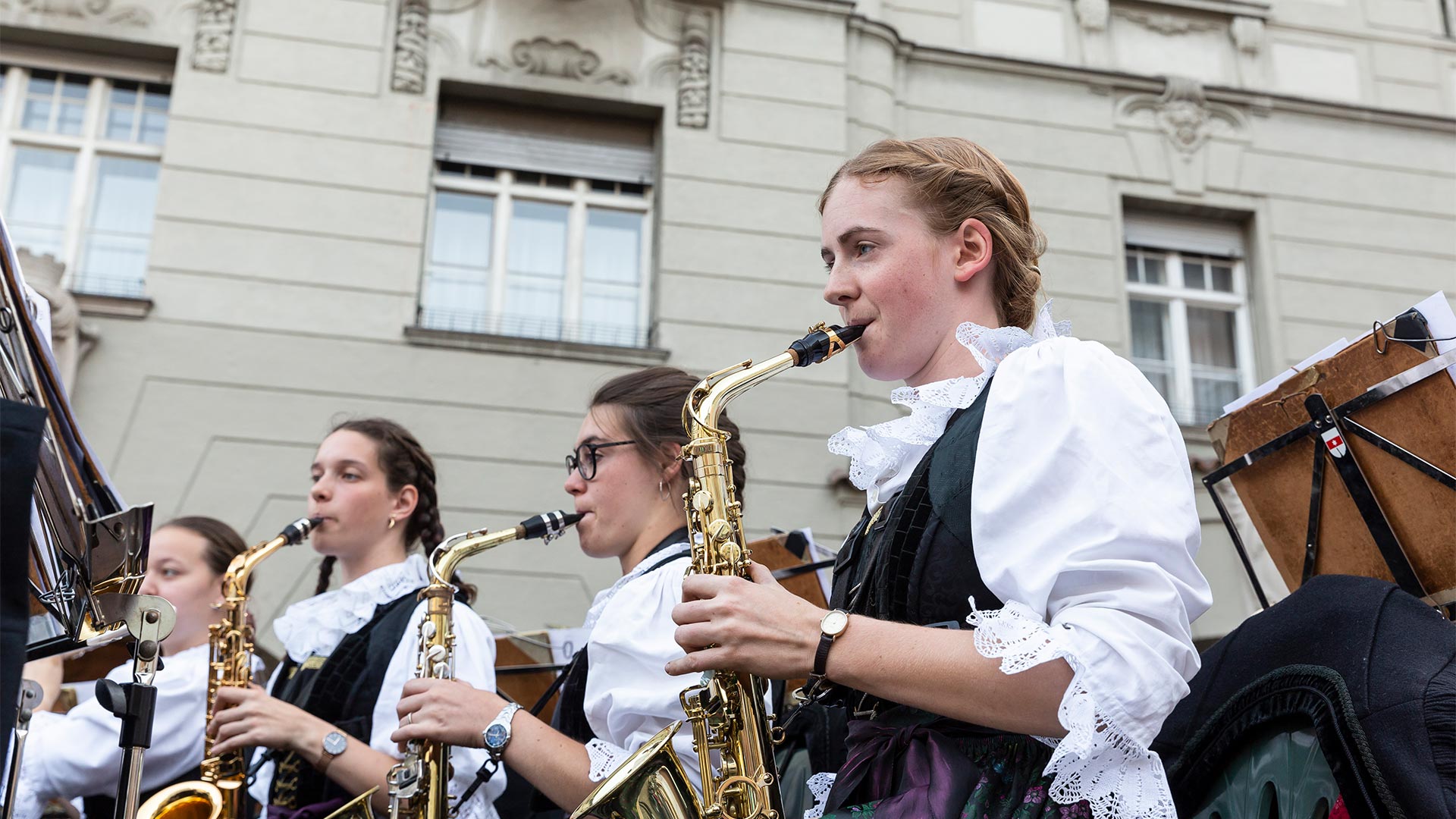 Im Vordergrund spielt ein Teil der Südtiroler Musikkapelle bei einer Musikveranstaltung in der Stadt Blasinstrumente.