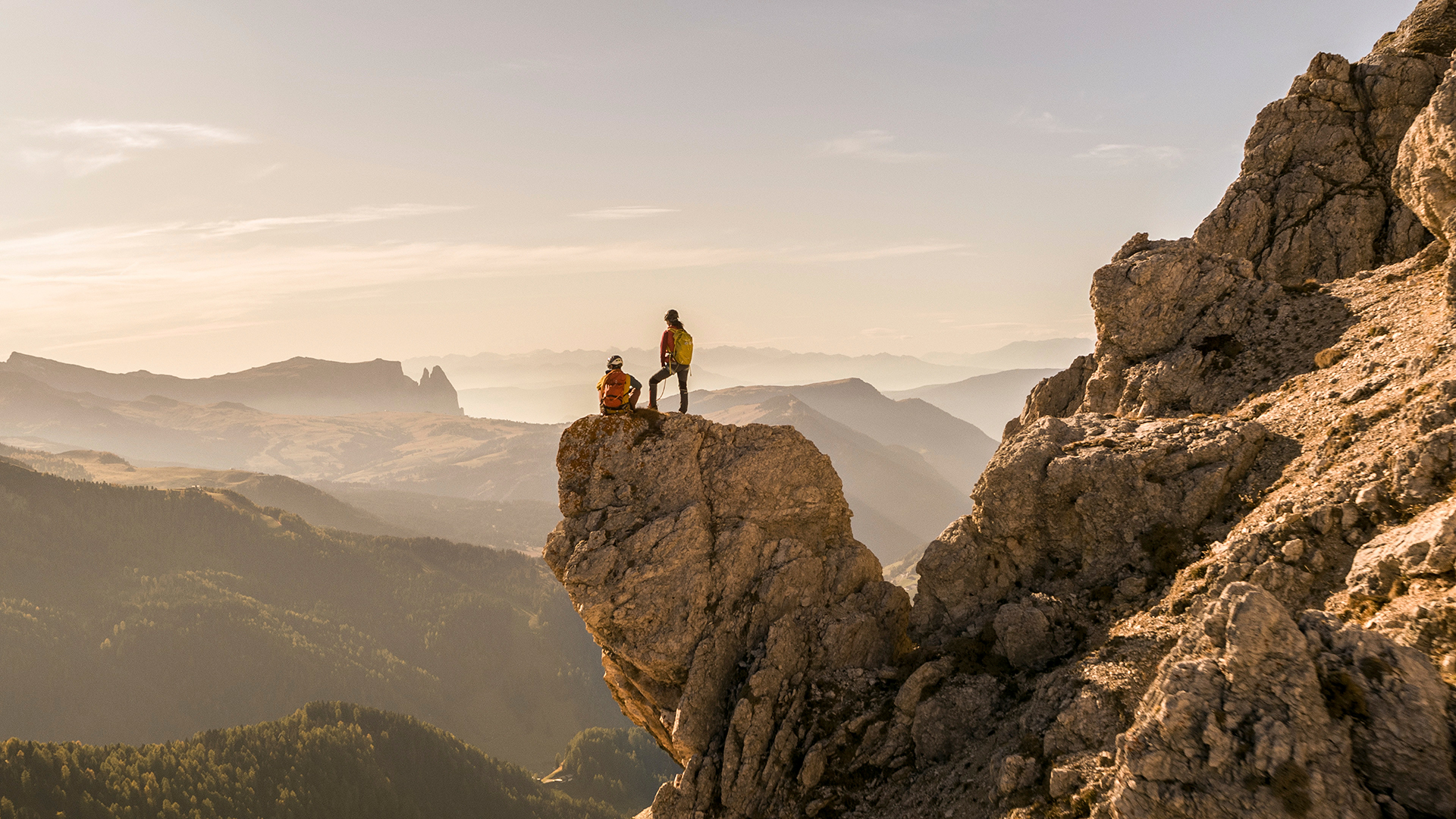 Due scalatori su un dirupo godono di una vista panoramica sui paesaggi naturali di Bolzano e si lasciano ispirare dalla loro bellezza .